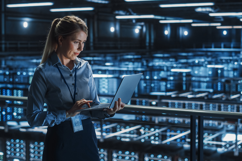 Frau im Serverraum am Laptop